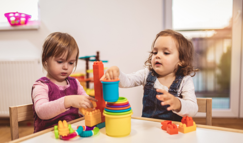 Two nursery aged children stacking cups