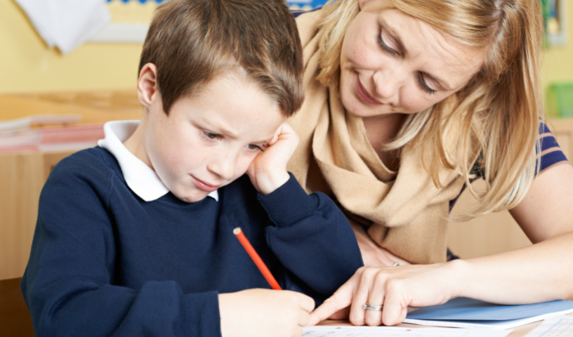Teacher and child looking over worksheet, child frowning at page