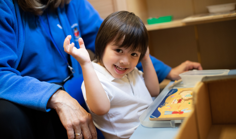 Child with arms up, smiling at camera