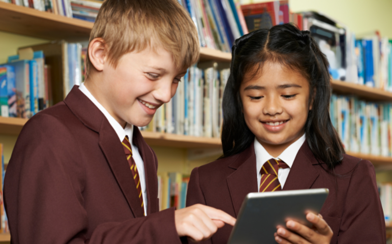 two pupils smiling together looking at iPad