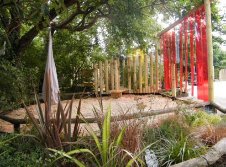 A sand play area slightly separated from the rest of the playground with loose coloured curtains.