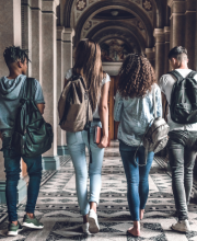 Young people walking down corridor together, rucksack on back, holding notebooks