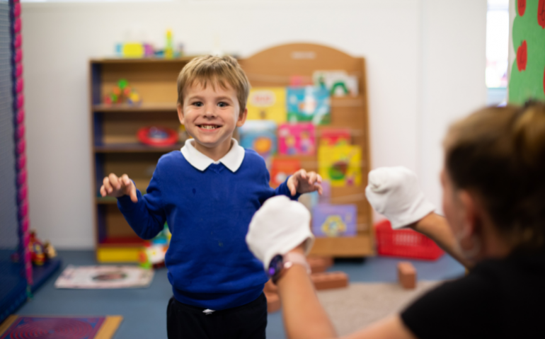 Boy in classroom, standing and smiling at camera