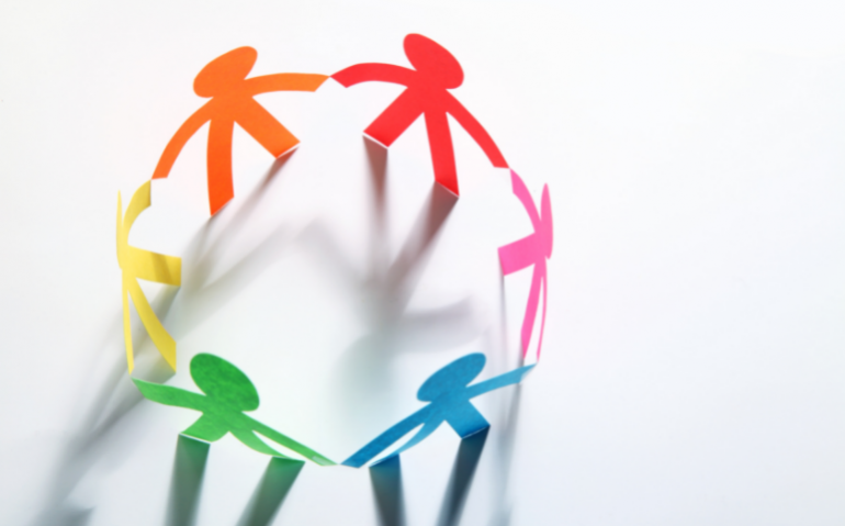 Photo of origami people holding hands, rainbow colours