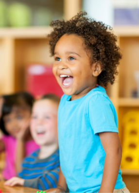 Preschool aged boy stood up at table and smiling