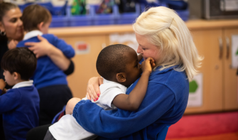 Practitioner hugging early years child