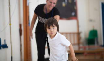 Child holding practitioner's hand, pulling them forward and looking at camera