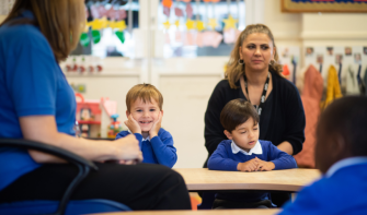 Boy in classroom, sitting at desk, smiling at camera