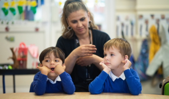 Two pupils sitting with teacher behind