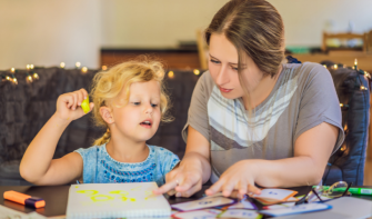 Mum and daughter looking at drawings together at table