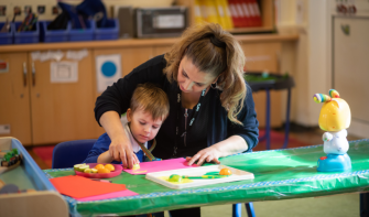 Child doing crafts in classroom with practitioner