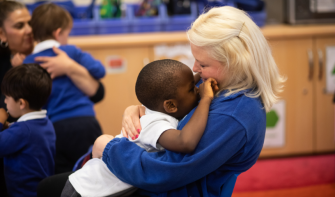 Practitioner and child - child leaning on practitioner and practitioner smiling