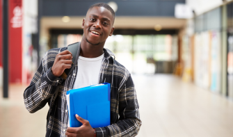 Sixth form student holding folder and smiling