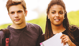 Two young adults, one holding note pad, looking at something behind camera