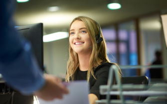 Young person with headset on, smiling at person stood behind the camera