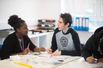 Teacher and post 16 learner, sitting at desk talking