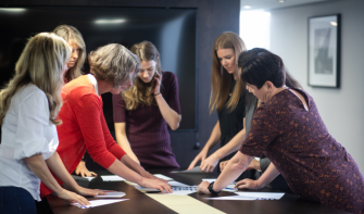 Members of the Autism Education Trust Team standing around table, all leaning in, sorting out papers.