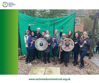 AET Team standing holding axes and shields, smiling at camera