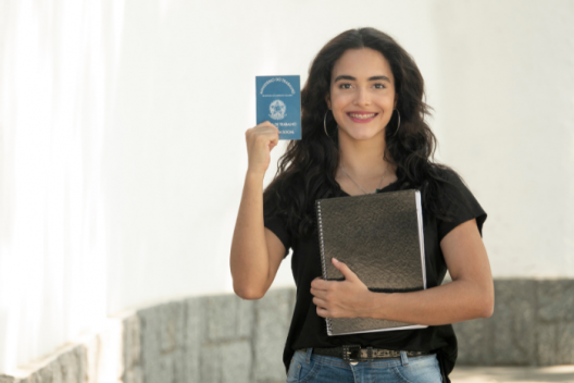 Young professional holding up work pass, smiling. 