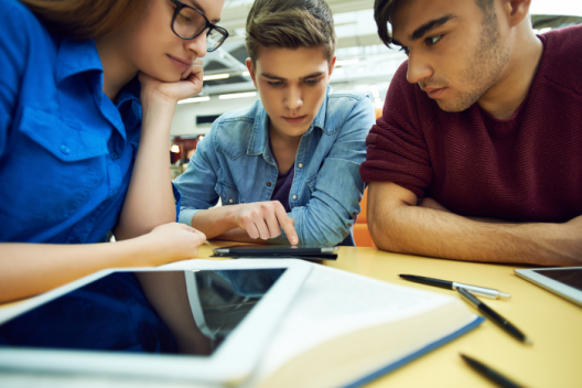 three pupils leaning over computer tablet together