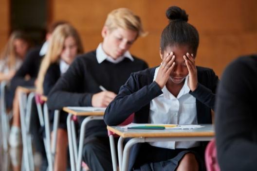 Pupil holding hands on face in exam hall