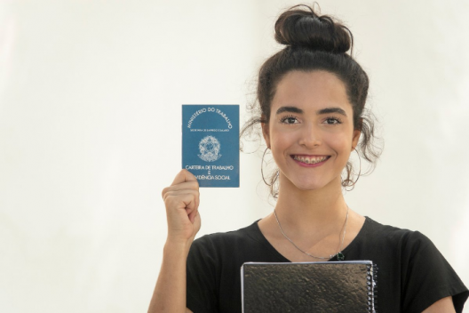 Young professional smiling and holding up work pass