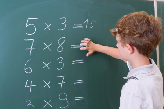 Pupil rubbing numbers off chalk board, doing maths sums