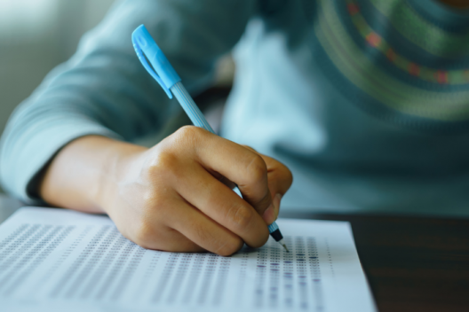 Student sitting at desk with exam paper and pen