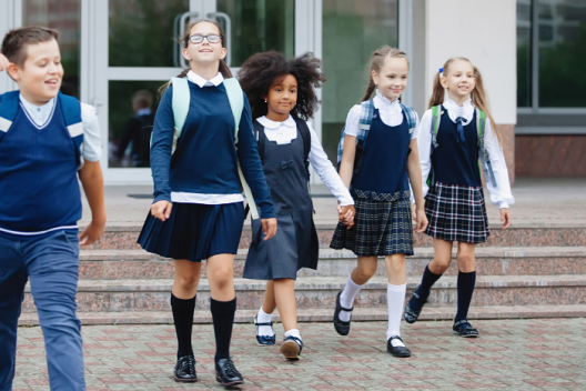 5 primary children in uniform, walking out of school building