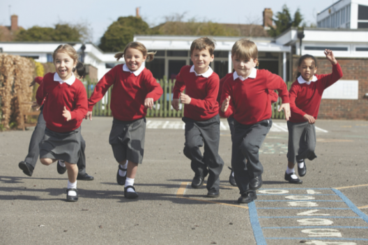 Primary school children in red uniform, running across playground