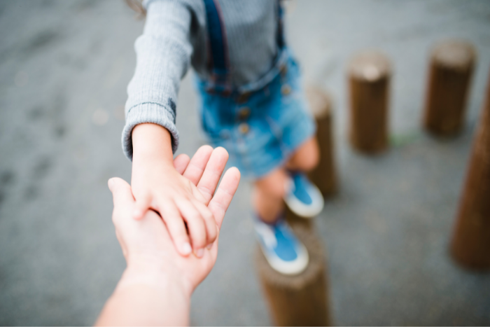 Close up of child's hand holding adult's.
