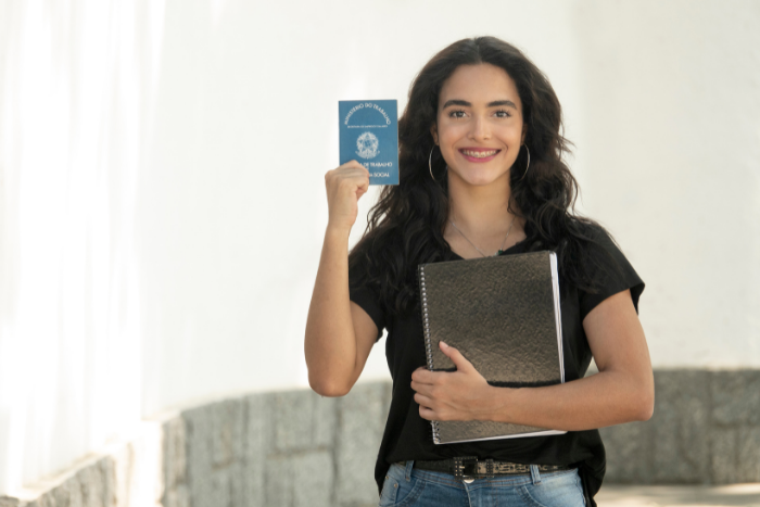 Young professional holding up work pass, smiling.