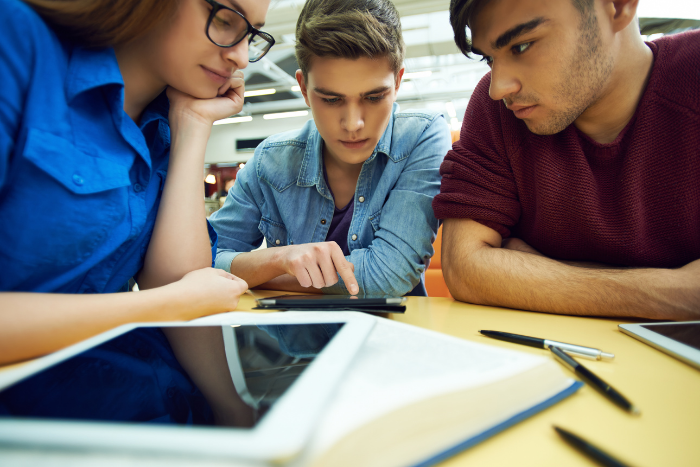 three pupils leaning over computer tablet together