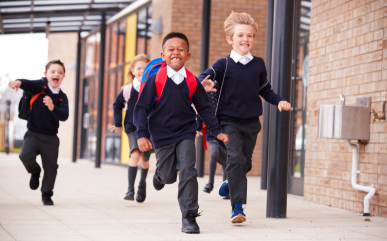 Pupils in school uniform, running together and smiling