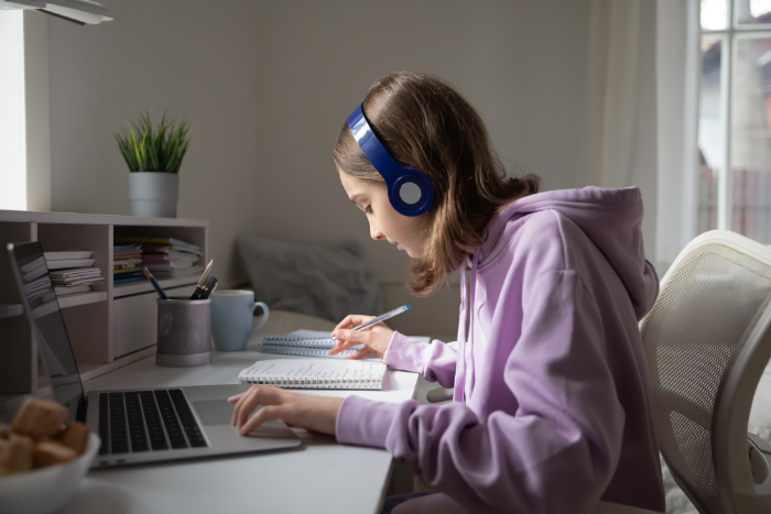 Pupil working at desk in bedroom with headphones on