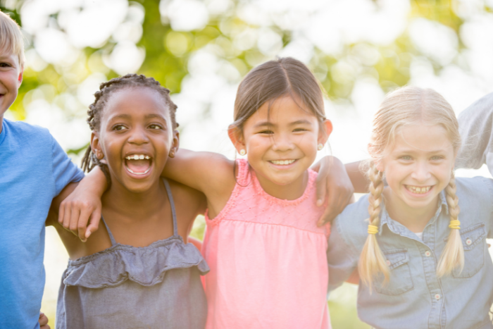 Three primary school pupils, arms around each other, smiling