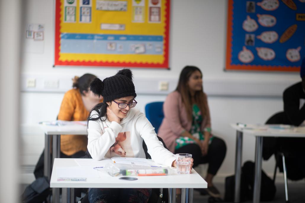 Post 16 pupil sitting at desk, smiling