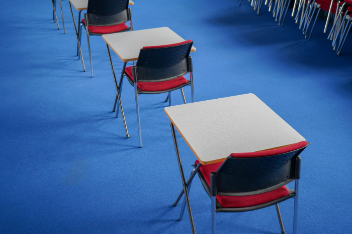 View from above of empty tables organised in one single row, evenly spaced. 