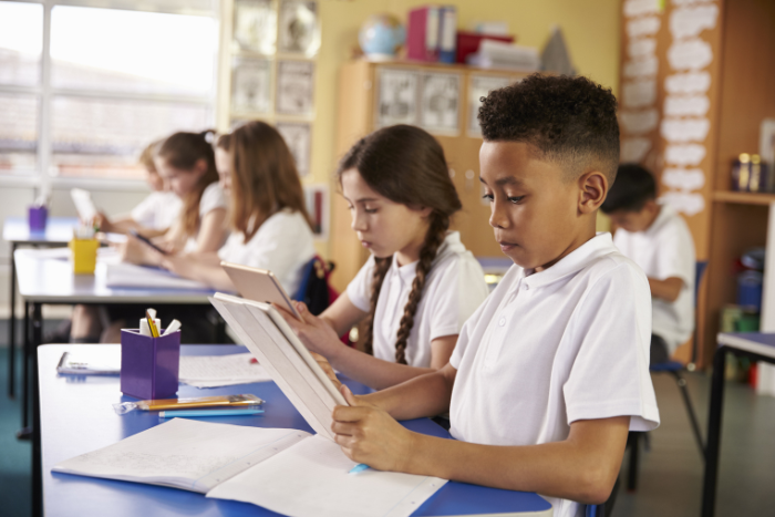 School pupil sitting in classroom at desk, looking at notebook